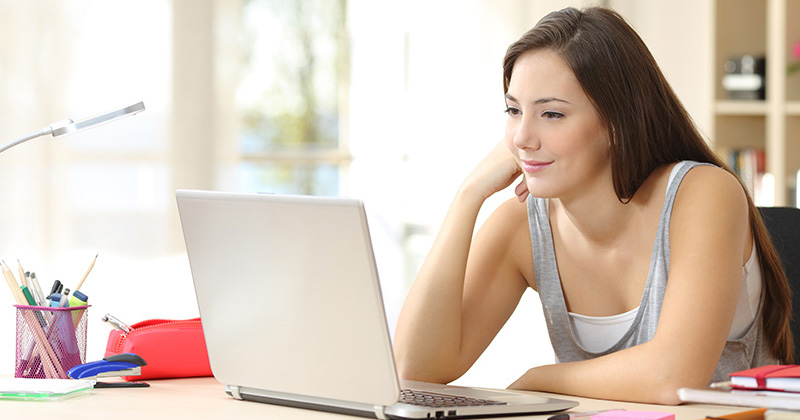 High school student looking at laptop screen at home