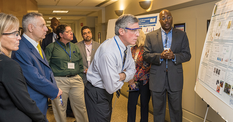 Thomas Epps, III (right), the Allan and Myra Ferguson Distinguished Professor, shared his group’s research on converting biomass into usable products, such as polymers that can be used in 3D printing, with Gov. Carney (center). 