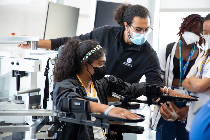 UD staff member demonstrates to students how to use physical therapy research equipment.