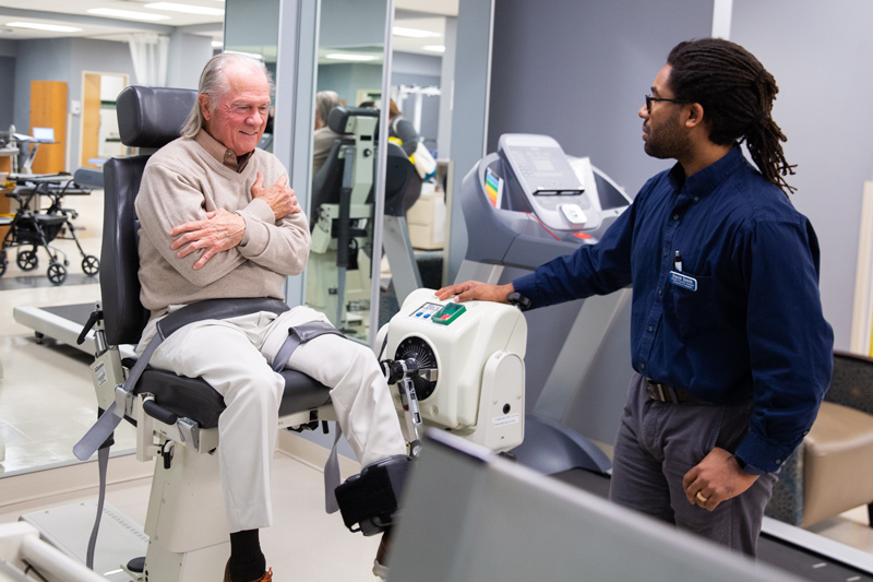 Physical therapy student David Smith works with a client to showcase operation of the kick machine in UD’s Physical Therapy Clinic. 