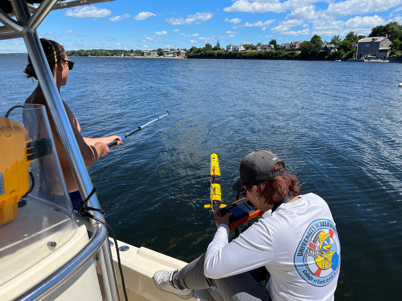 Master’s student Grant Otto (left) helps orient the AUV away from the boat while master’s student Sun Woo Park initiates the mission go command from the remote control. The Iver3 AUV is setting off to map lakebed anomalies off the War of 1812 battlefield site.