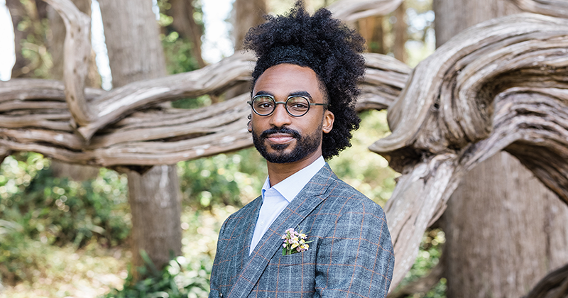 Destin Jenkins standing headshot, in front of a twisted wood fencew