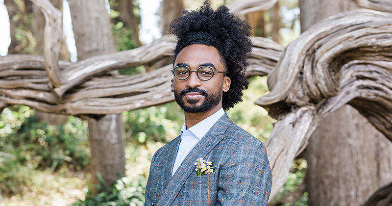 Destin Jenkins standing headshot, in front of a twisted wood fencew  