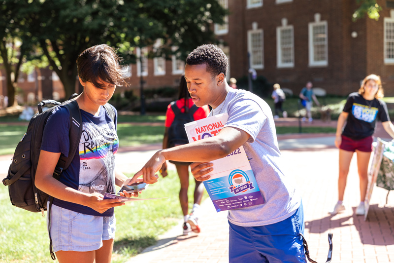 Elijah Simmons (right), a senior communications major at UD, encourages first-year student Anu Buddhikot to register to vote.