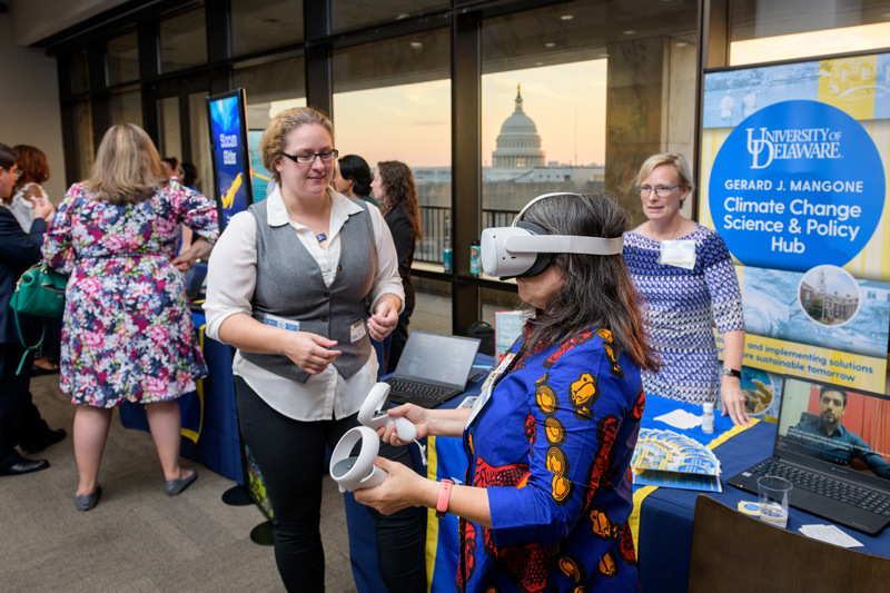 With the U.S. Capitol in the window, Kelly Cobb, associate professor of fashion and apparel studies at the University of Delaware, gets a virtual-reality look at how sea-level rise would affect Bowers Beach in Delaware as A.J. Siders and Dana Veron, co-directors of the University of Delaware’s Gerard J. Mangone Climate Change Science and Policy Hub, look on. With the U.S. Capitol in the window, Kelly Cobb, associate professor of fashion and apparel studies at the University of Delaware, gets a virtual-reality look at how sea-level rise would affect Bowers Beach in Delaware as A.J. Siders and Dana Veron, co-directors of the University of Delaware’s Gerard J. Mangone Climate Change Science and Policy Hub, look on.