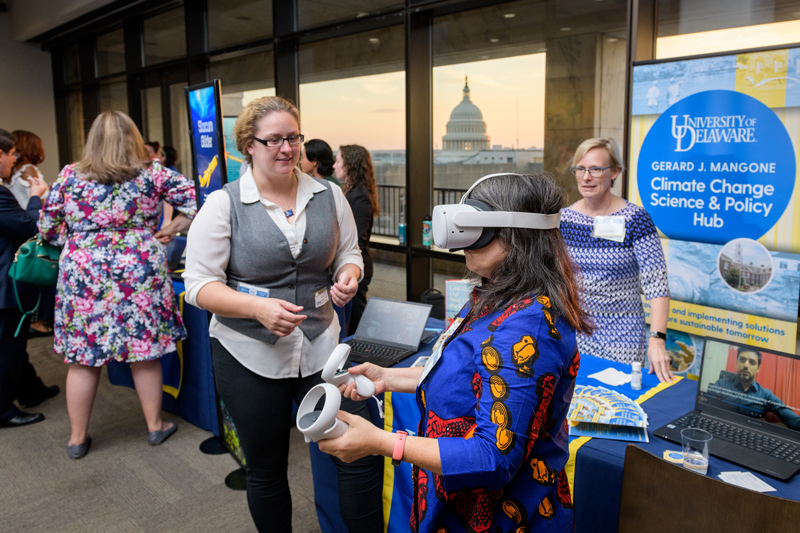 With the U.S. Capitol in the window, Kelly Cobb, associate professor of fashion and apparel studies at the University of Delaware, gets a virtual-reality look at how sea-level rise would affect Bowers Beach in Delaware as A.J. Siders and Dana Veron, co-directors of the University of Delaware’s Gerard J. Mangone Climate Change Science and Policy Hub, look on.