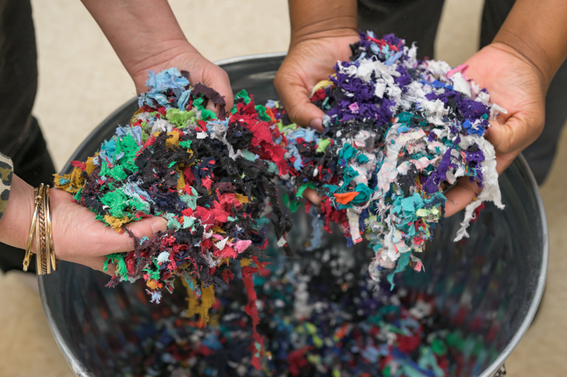 Hands hold shredded textiles with the potential to become erosion mats, landscaping fabric and more through work underway by University of Delaware researchers and students.