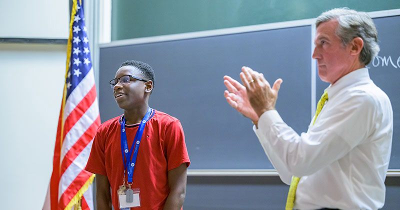 Christiana High School’s Daniel Okagbare (left) wraps up his policy pitch to Gov. John Carney at Kirkbride Lecture Hall, where participants in the Governor’s School for Excellence were challenged to create solutions to pressing social problems.