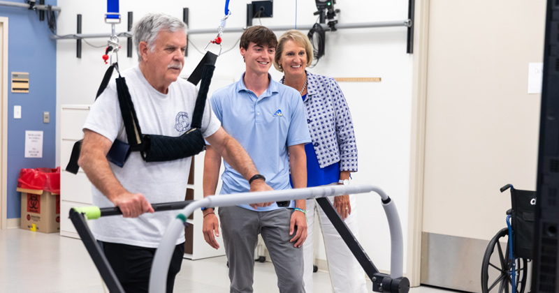 Stroke survivor Larry Christian walks on an adaptive treadmill as part of ongoing stroke recovery research led by Darcy Reisman (right), chair of the Department of Physical Therapy.  Rising sophomore Matt Carr (middle) obtained the Peter White Fellowship which allowed him to work alongside Reisman in her lab this past summer. 