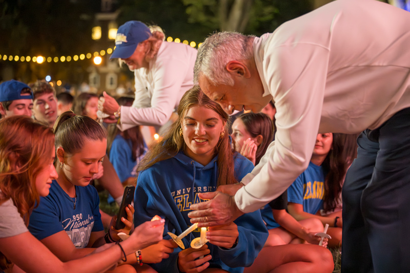 UD President Dennis Assanis lights a candle for MacKenzie Bowman (center), who said the Induction Ceremony served as a reminder to make the most of the each moment in a college career.