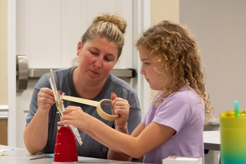 Mom and daughter Stacey Lambertson and Kenzie use art supplies to make a renewable energy prototype.