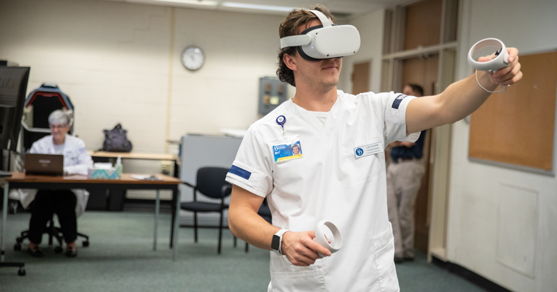 Senior honors nursing student Luke Stuchlik said he feels as though he’s been transported into a hospital room as he works to care for four patients as part of a new virtual reality simulation offering in the School of Nursing.
