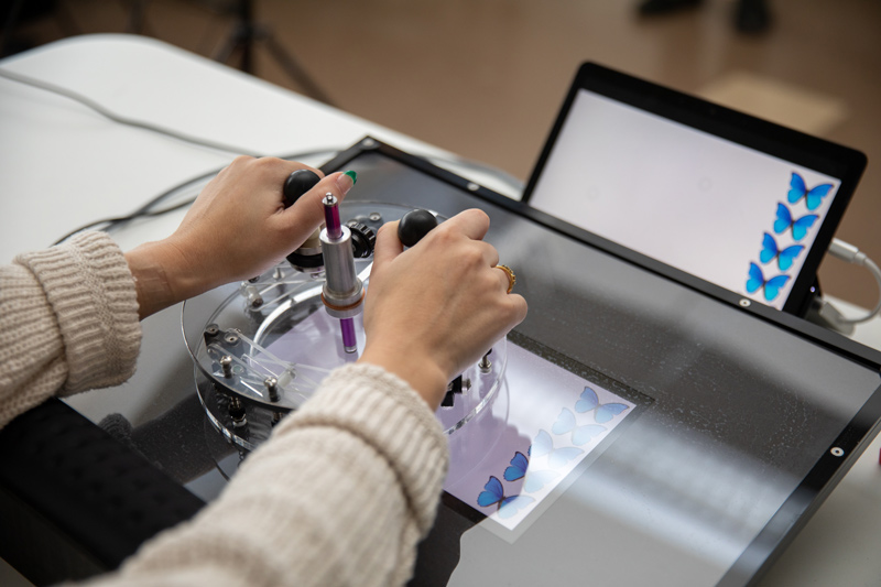 Junior mechanical engineering major Sara Dugan demonstrates the latest version of PushnDraw® that she helped design. The device allows children with upper limb disabilities to play games, navigate mazes and draw freely. 