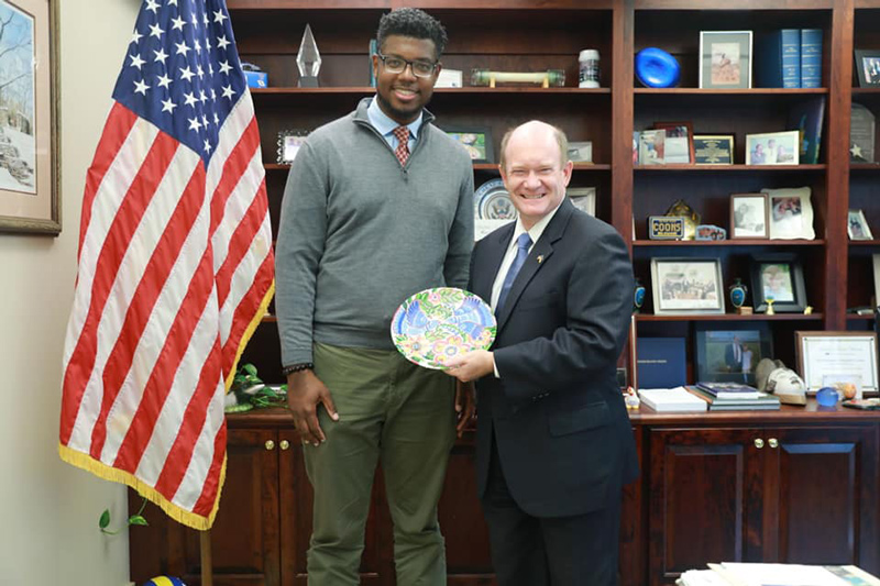 Atnre Alleyne thanks Delaware U.S. Sen. Chris Coons for his work on behalf of Ukraine with a gift made by a Ukrainian refugee.