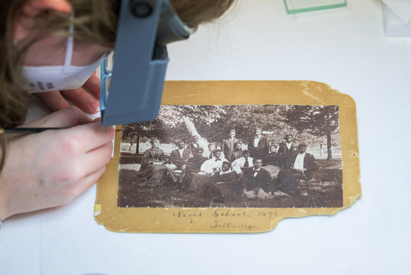 A graduate student painstakingly repairs a photograph of the Talladega Night School Class of 1896. A graduate student painstakingly repairs a photograph of the Talladega Night School Class of 1896.
