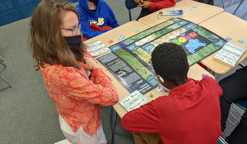 To help raise geography awareness, Tracey DeLiberty plays a board game with students. The game was developed by DeLiberty and Mary Shorse with AmericaView in collaboration with the United States Geological Survey (USGS) and NASA.