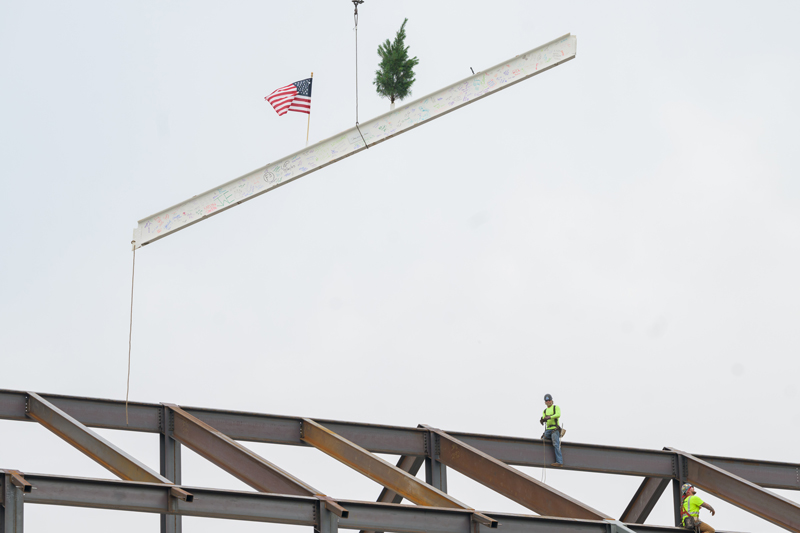 Iron workers get into position as the final beam of Building X is moved into place on Thursday, July 20.