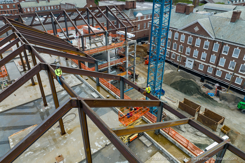 Two iron workers await the arrival of the last steel beam during the “Topping Out” event at Building X, a new “science collider” laboratory under construction at the University of Delaware.