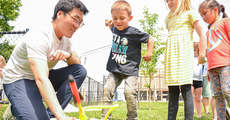Graduate student Tony Liang (left) helps students launch their own miniature rockets into the sky. 