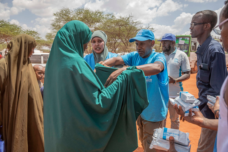 Staff members from the United Nations Refugee Agency, the government of Ethiopia and the World Food Programme distribute high energy biscuits to newly arrived refugees being relocated to Mirqaan Settlement after fleeing the fighting in neighboring Somalia.