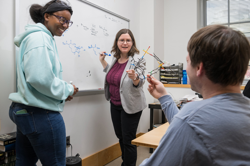 Mary P. Watson (center), professor of chemistry and biochemistry, has been recognized for her success in developing new methods to construct organic molecules, including a tool her team established in 2017 that has led to a surge of interest among chemists worldwide. Graduate students Bria Garcia (left) and Cameron Twitty are with her in a classroom.