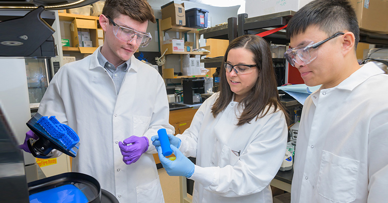 Professor Cathy Fromen (center) is in the lab with doctoral candidates Ian Woodward (left) and Yinkui Yu. Once the researchers find the best design, the goal is to print out lattices using elastic materials and set up a full-scale version of a lung that can “breathe.”