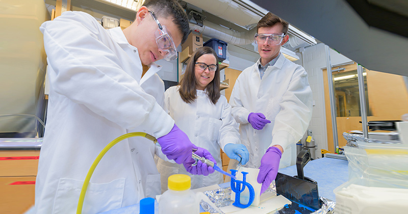 Professor Cathy Fromen (center) in the lab with doctoral candidates Yinkui Yu (left) and Ian Woodward. The group will combine research and outreach to K-12 students to help inspire the next generation of scientists.