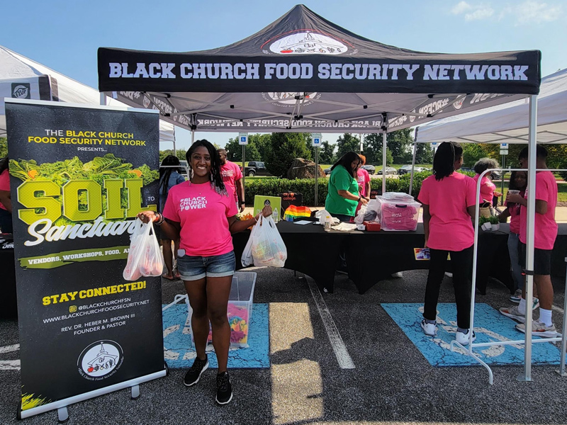 Africana Studies graduate student Austen-Monet McClendon displays bags of fresh produce available at the Soil to Sanctuary markets organized by the Black Church Food Security Network. The events provide fresh produce to neighborhoods suffering from food injustice.