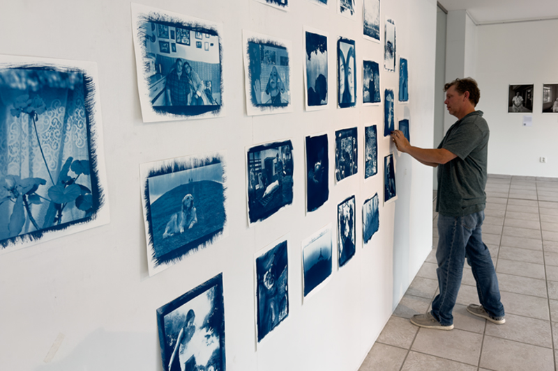 Jon Cox hangs photographs on a gallery wall