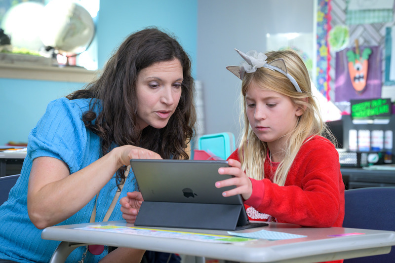 A teacher at CEHD’s The College School works with a student on a writing assignment using a computer. A teacher at CEHD’s The College School works with a student on a writing assignment using a computer.