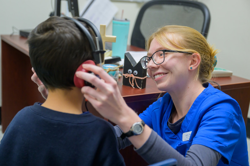 Joanna Maier, a graduate student in speech-language pathology, checks for a good headphone fit and placement before starting a hearing screening at Holy Angels School in Newark. 