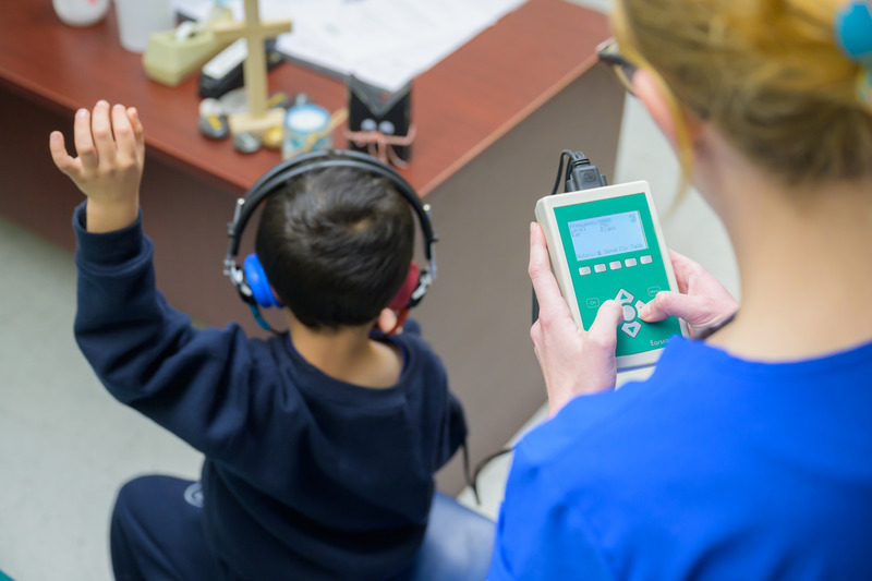 Joanna Maier, a graduate student in UD’s Speech-Language Pathology program, asks children to raise a hand when they hear a beep as part of state-mandated hearing screenings at Holy Angels School in Newark. 