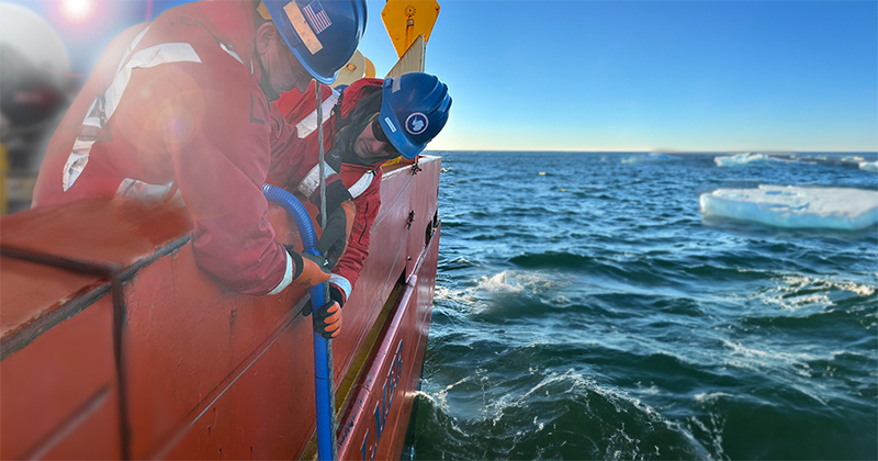 A marine technician holds the wire steady while Marsay (left) secures a hose to collect seawater samples from the back deck.