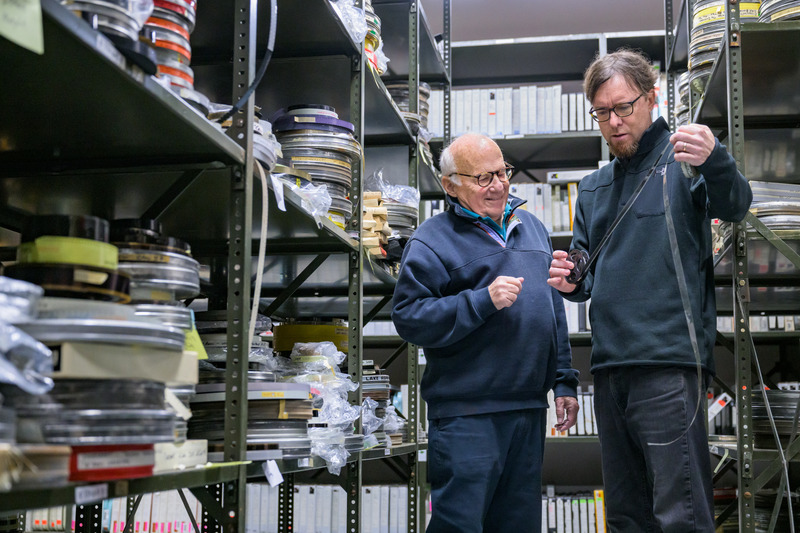 Kevin Martin (left), curator of audiovisual collections and digital initiatives at the Hagley Museum and Library, and Jim Culley, alumnus of UD’s MALS program, examine a portion of the thousands of sponsored films from Culley’s family film studio that are now being preserved and digitized at Hagley.