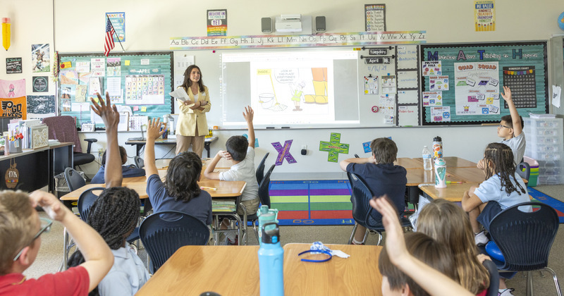 JPMorgan Chase’s Kyra Giakas reads a comic book with lessons on debt and interest to students at Newark Primary Charter School on April 16. The event was part of Teach Children to Save Day in Delaware. 