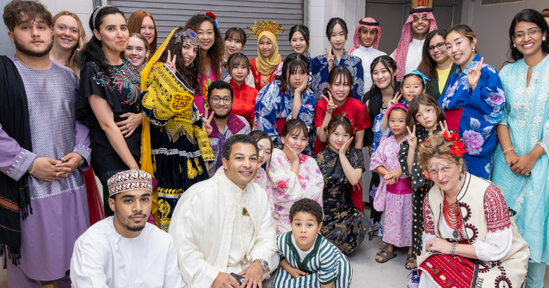 Untitled design - 1 Students and staff gathered together in various cultural attire.