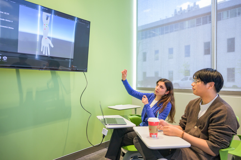 Student software developers Brishna Nazari and Joshua Taing discuss how sensor data displayed on a computer software program will help users visualize how well they performed during their blood draw practice. Student software developers Brishna Nazari and Joshua Taing discuss how sensor data displayed on a computer software program will help users visualize how well they performed during their blood draw practice.