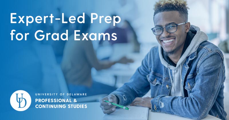 Young man in classroom, taking notes at a table.