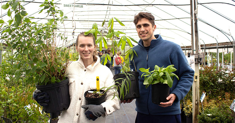 Two customers select their plants inside a greenhouse at Ag Day 2024.