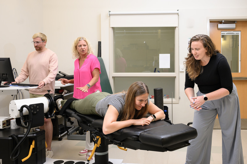 Doctoral candidate Andy Smith and professor Karin Grävare Silbernagel assess doctoral student Madeleine Krotine’s ankle strength, as assistant professor Stephanie Cone offers encouragement.
