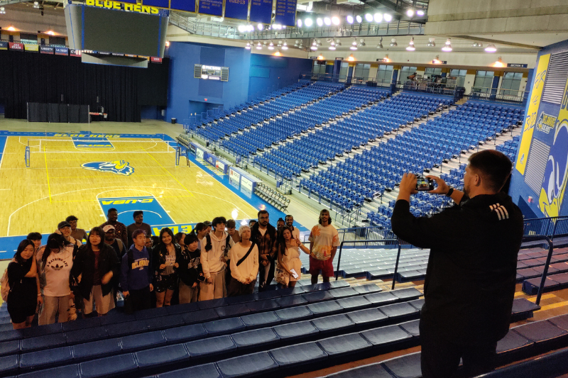 Austin Van Treuren, UD’s assistant athletic director of marketing and engagement, photographs the international students in the Frank Acierno Arena in the Bob Carpenter Center. 