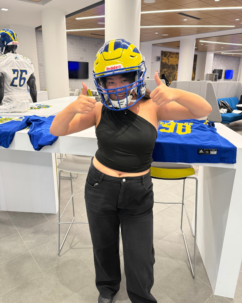 An international student tries on a Blue Hens football helmet during the tour.