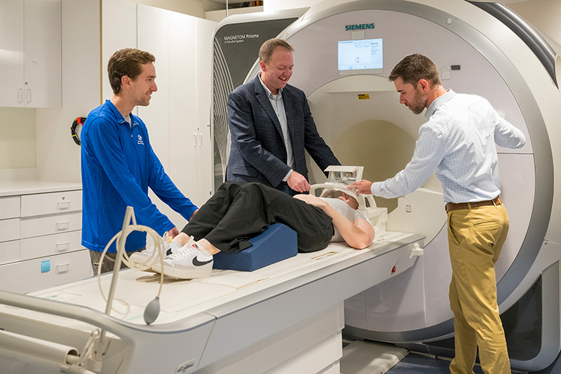 The DCF grant will fund the purchase of a new state-of-the-art MRI machine on STAR Campus to support DECCAR executive committee member Curtis Johnson’s (inner left) work with DECCAR director Christopher Martens (right) to use magnetic resonance elastography to explore links between brain stiffness and cognitive impairment. 