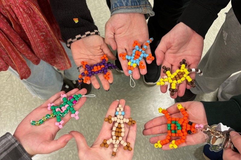 Members of the Delaware Herpetology Club display handmade frog and lizard keychains. Club activities include presentations, crafts, and outdoor excursions to observe reptiles and amphibians. 
