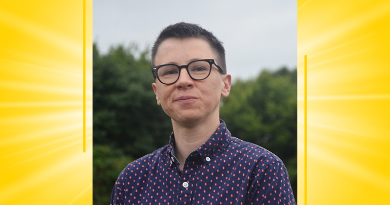 headshot of professor on a yellow background