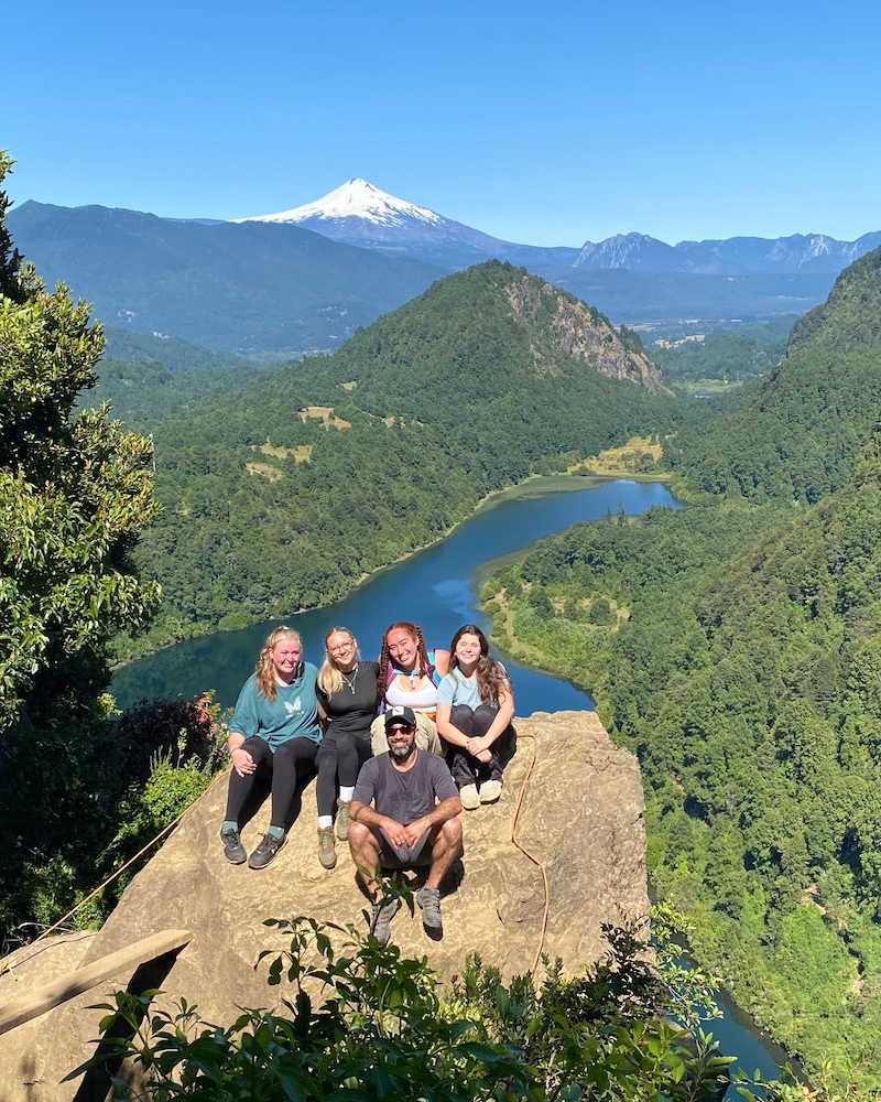 Agnes Cruz, Ava Ferry, Sophia Freeman and Helena Owen relax with the in-country guide, Francisco Maldonado, at an overlook in a Mapuche Indigenous community. 