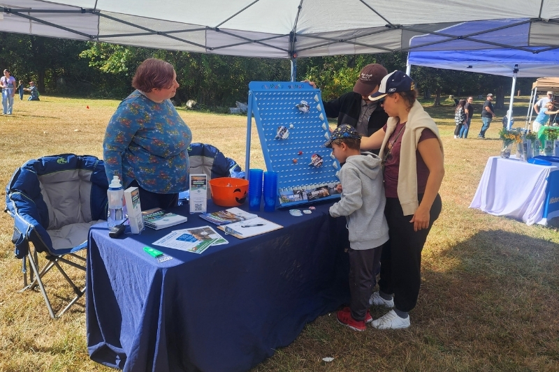 Lee Aiken, DNREC climate policy planner and UD Class of 2018 alumna, helps a family to learn more about climate risks while playing "Climate Plinko" at Blackbird Creek Fall Fest. 