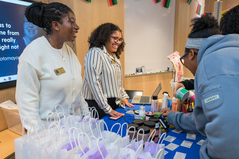 Valerie Issa (left), programming intern for student diversity and inclusion, and Chelsea Cohen, program coordinator of student diversity and inclusion, pass out hair product goodie bags and give hair tips to attendees of CIE’s Hair Product Exchange event. 