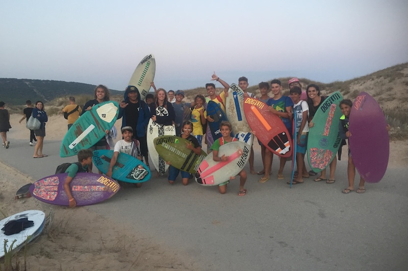 Okoniewski, standing with a white board, connected with local skimmers during a trip with Team USA to Los Caños de Meca, a bohemian village on the southwest coast of Spain, known for unpredictable surf. 