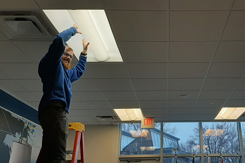 Sam Romano inspects a lighting fixture. Switching to LED lighting is one common recommendation auditors make to help facilities reduce electricity consumption.